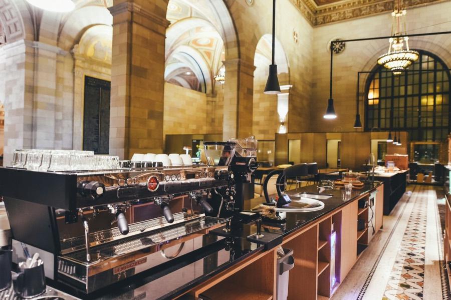 A grand café hall with espresso machines along a long bar