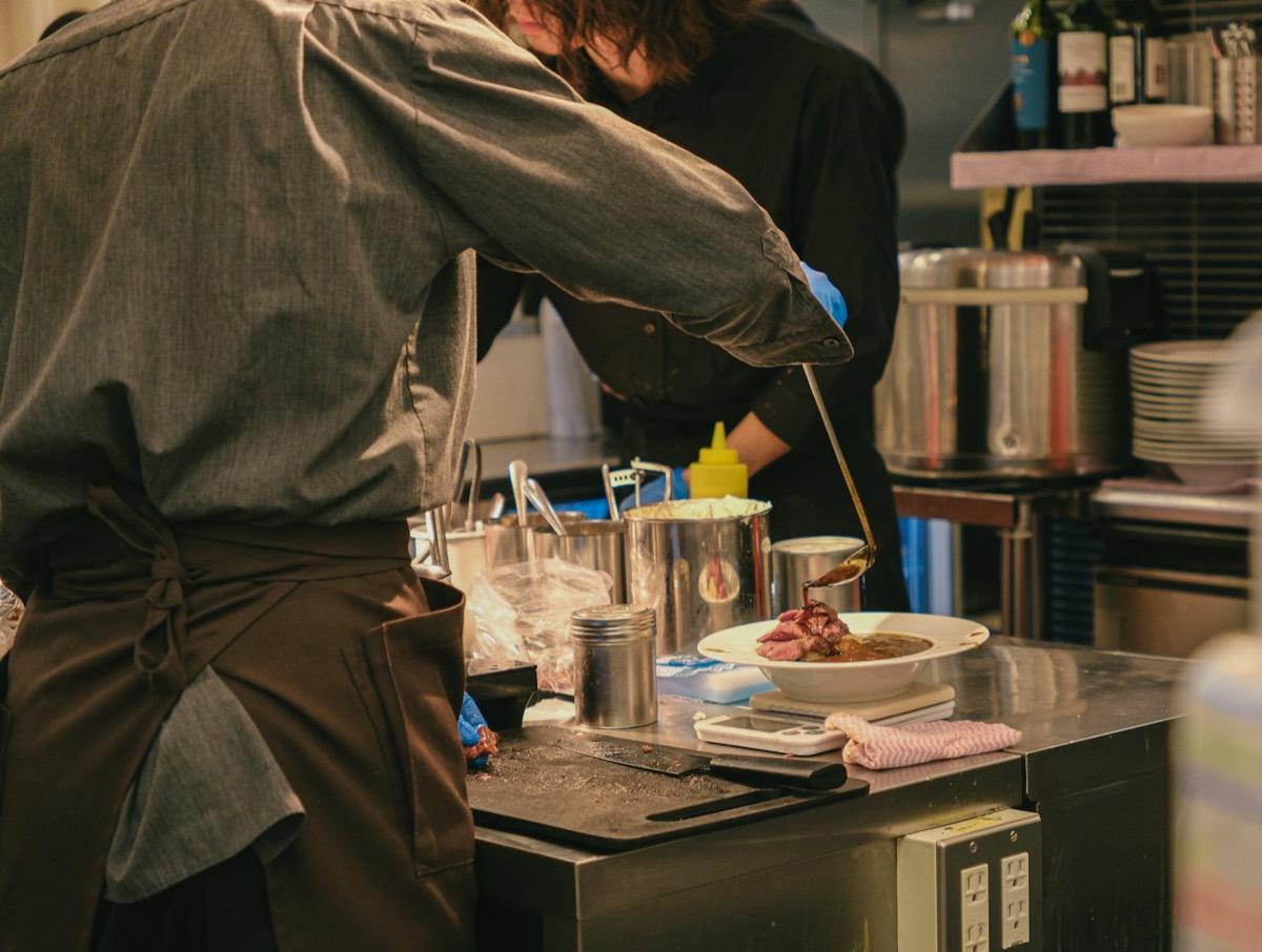 A chef plating a dish at the kitchen pass