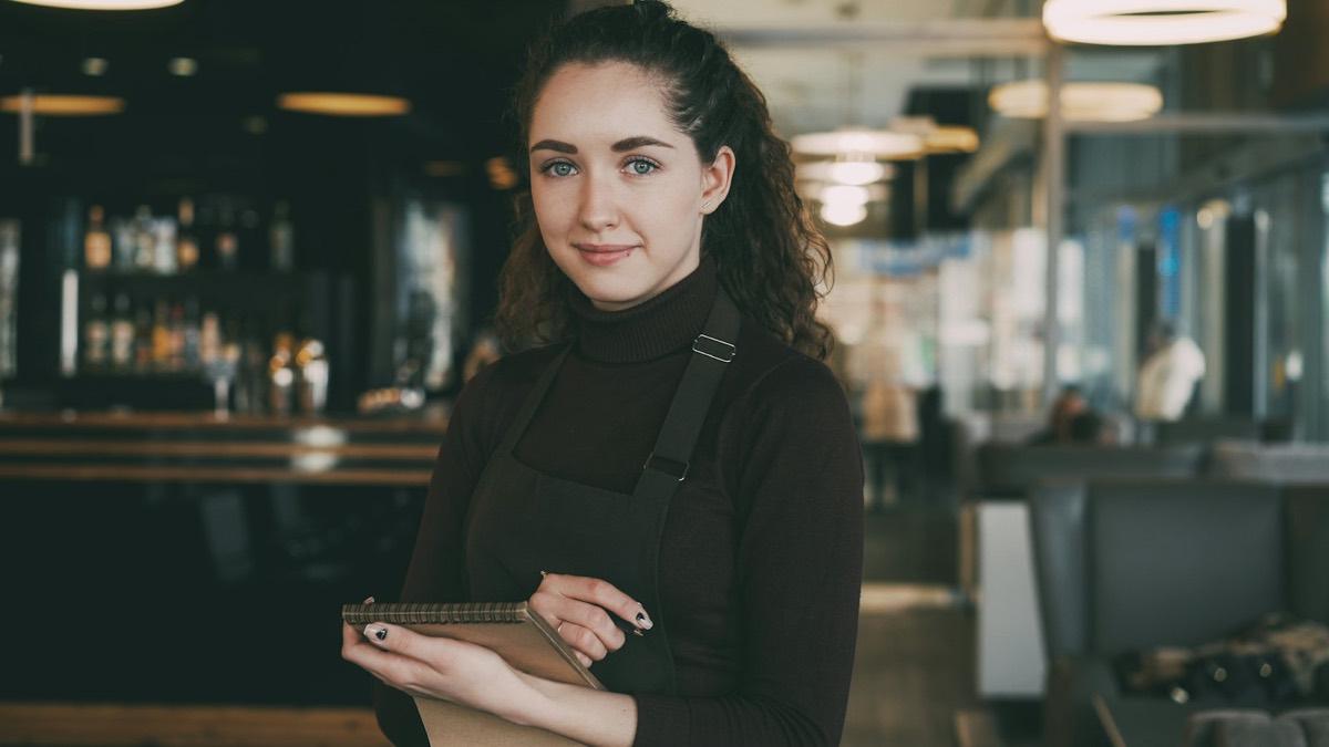 A smiling server in an apron, ready to take an order